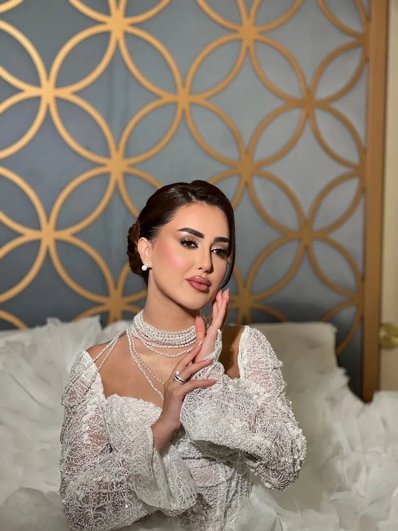 عروس بفستان أبيض دانتيل وتسريحة مرفوعة ولآلئ